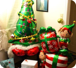 a green, red, and white display of balloons in the shapes of a Christmas tree, wrapped gifts, and elves