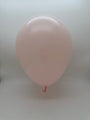 A single 23'' Balloonia Latex Balloons Professional Line Matte Baby Pink balloon is fully inflated and floating against a plain, light gray background, with the knot and part of the neck visible at the bottom.