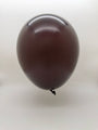 A single 12'' Balloonia Latex Balloon in Standard Chocolate from the Balloonia Professional Line floats against a plain white background, its tied end hanging downward.