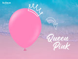 A large Queen Pink 12″ Kalisan latex heart balloon, featuring a white crown illustration and “Queen Pink” written in white script, floats above a beach scene with waves.